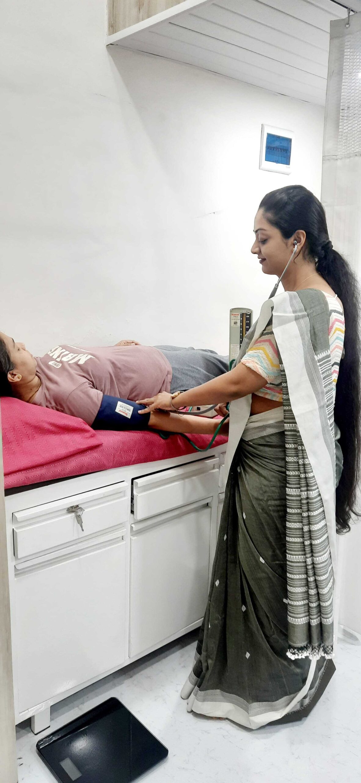 Doctor checking a pregnant woman's blood pressure at a clinic in Navi Mumbai.