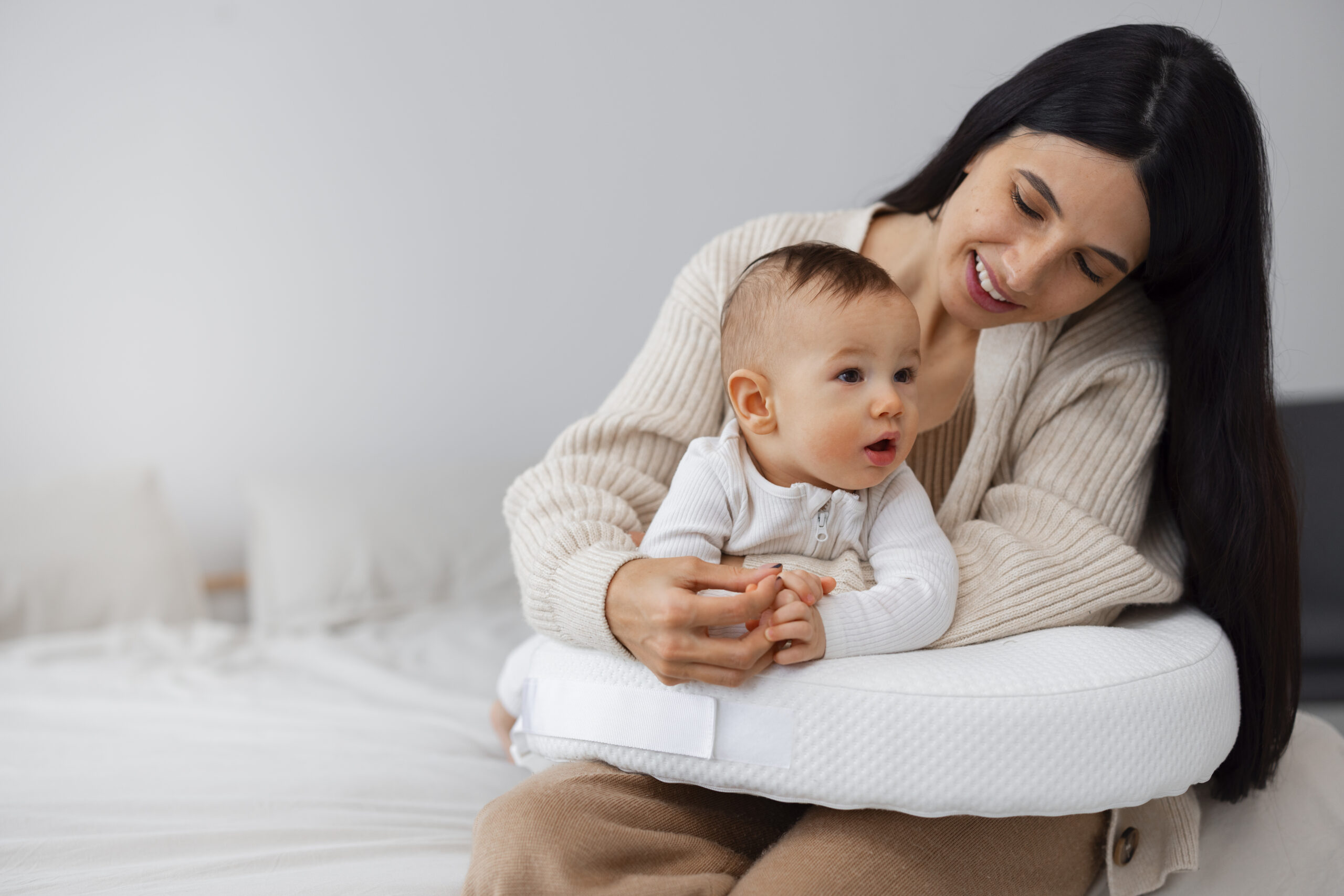 A mother lovingly holds her baby on a bed, fostering a sense of care and warmth.