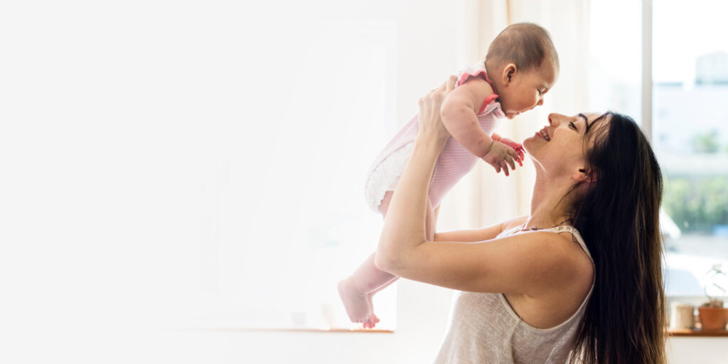 A mother joyfully lifts her baby in a bright and welcoming home environment.